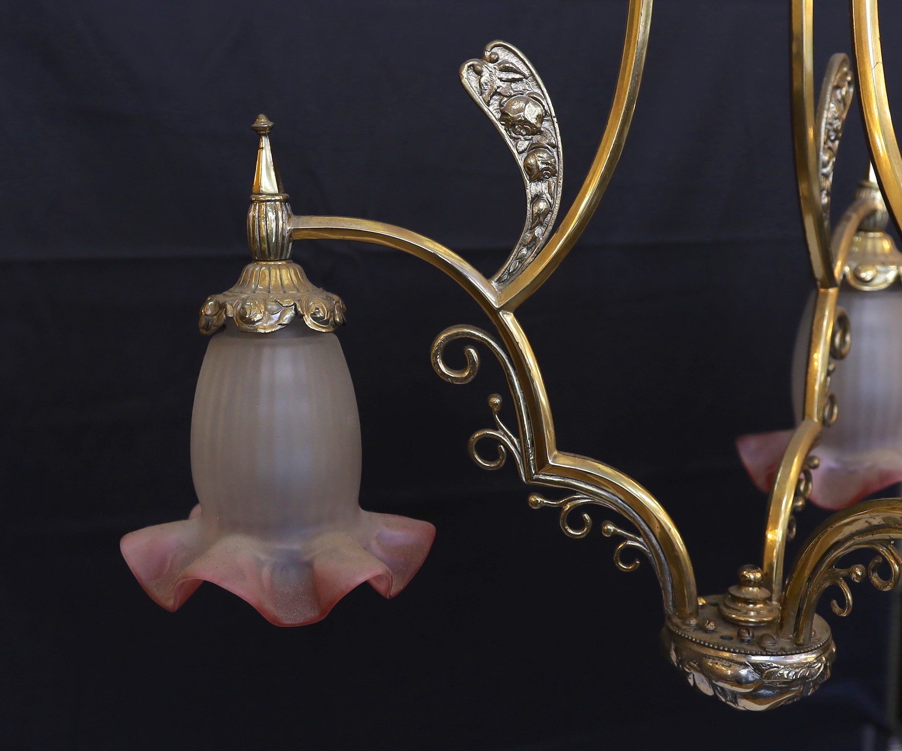 A 1930s French brass three light chandelier with cranberry tinted frosted glass shades, height 70cm. width 60cm